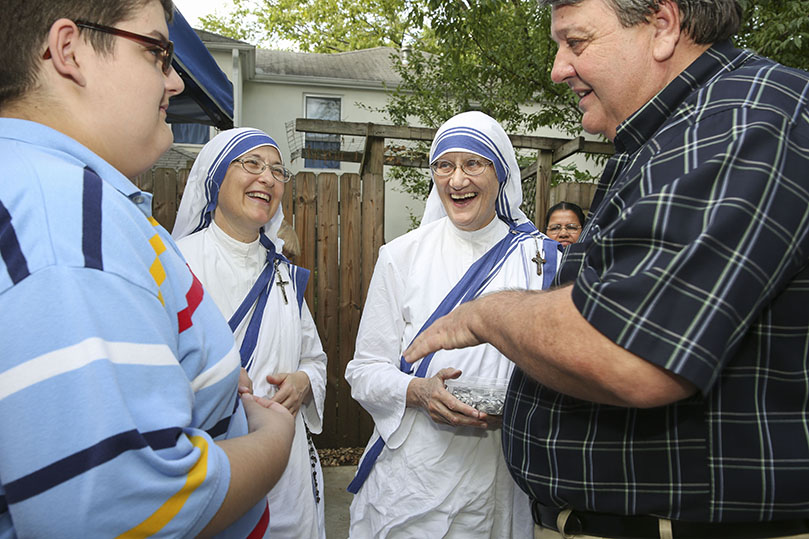 After being introduced to Sister Mary Prema, MC, background right, by Sister Rita Marie, MC, background left, mother superior of Atlanta’s Gift of Grace House, Micah Jennings, foreground right, tells his son, Micah, what a joy it’s been to be a Missionaries of Charity volunteer for the past 25 years. Jennings was one of several volunteers who helped renovate the house before it officially opened in 1994 as a home for women with AIDS. Photo By Michael Alexander