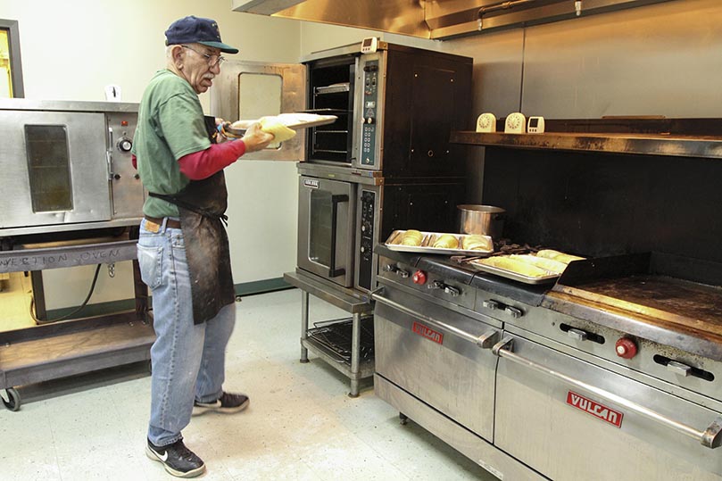 Bill Lucas, the team leader for the Polish nut roll making project, takes the first batch of rolls out of the convection oven. Later in the day, they will use all three convection ovens and the two regular ovens. Photo By Michael Alexander