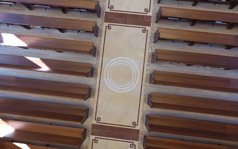 There are five circles like this one inside a bamboo mat border going down the center aisle. They represent five of the seven sacraments, beginning with the baptismal font in the narthex and ending with the altar in the sanctuary. The three circles within each other represent the Trinity. Drone Photo By Allen Kinzly