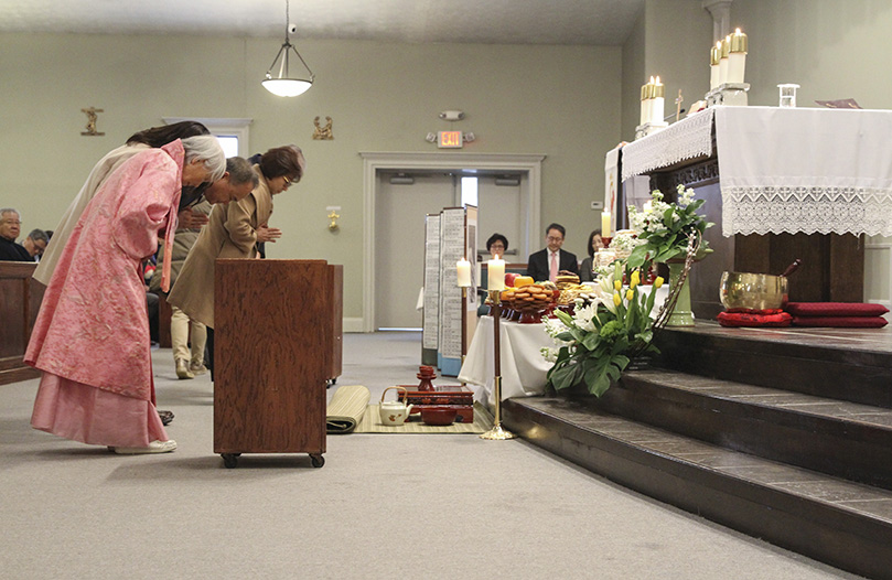 Members of the Song family bow before the special altar set up for the celebration of the Lunar New Year at St. Andrew Kim Church, Duluth. The gesture pays homage to ancestors and deceased relatives. Photo By Michael Alexander