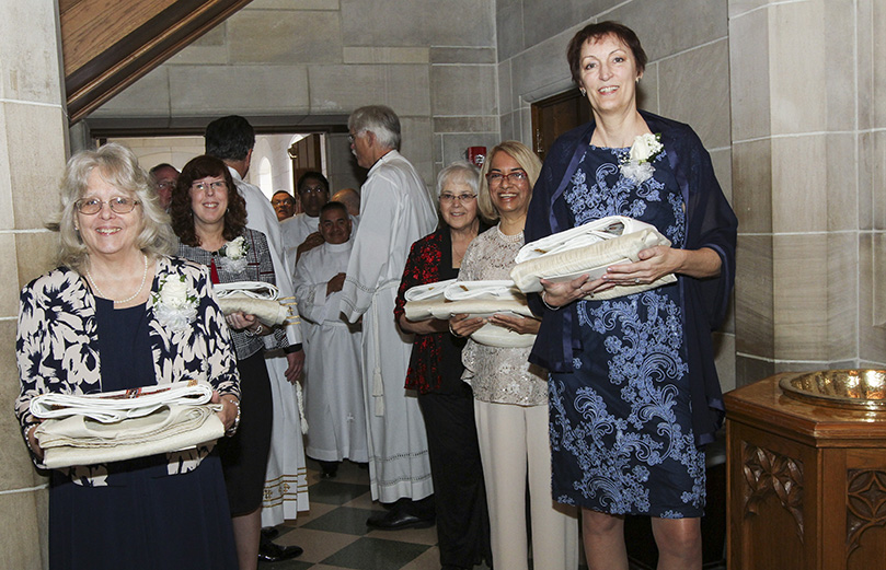 Five of the eight wives are seen gathering in the narthex, holding their husbands' stoles and dalmatics, at the front of the impending procession. They include (clockwise, from foreground left) Jacqueline Odom, Beth Windon, Renee Ponce, Daphne Lobo and Jean Goodwin. Photo By Michael Alexander