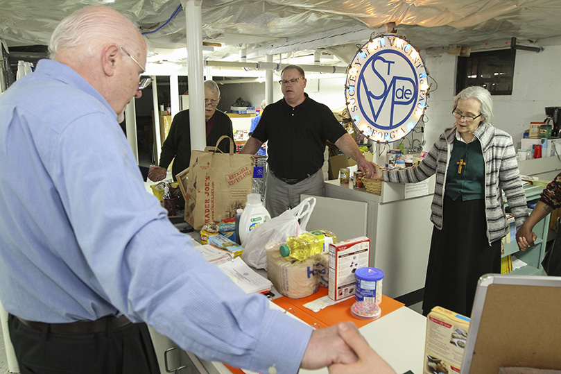 Volunteers and one of the clients stop to pray, Feb. 11, at St. John Neumann Church’s St. Vincent de Paul Society food pantry. Photo By Michael Alexander