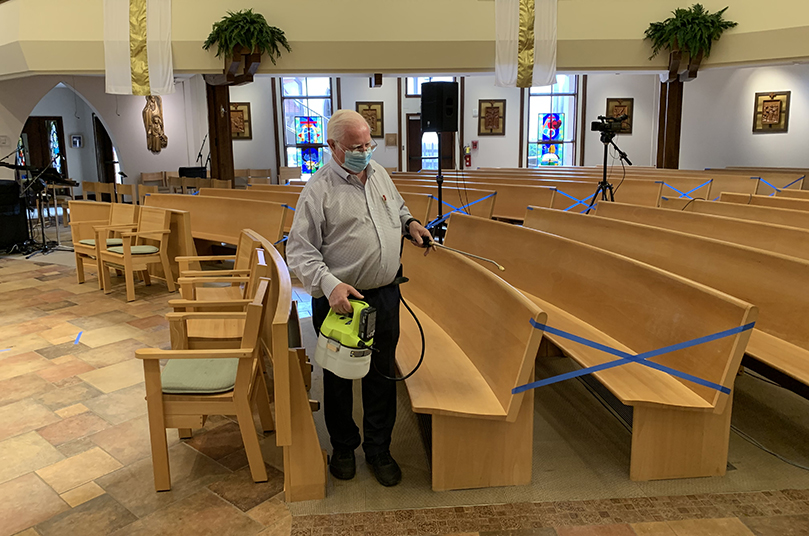 Liam Farrelly, director of operations at St. Ann Church, Marietta, conducts a trial run of the disinfecting procedures that will take place between each Mass. The weekend Masses at the parish were cut from eight to four. Reservations are required to attend the public Masses, which are now held at 5p.m. Saturday and 8:30a.m., 12:30p.m. and 6p.m. Sunday. Photo By Jim Herrel.