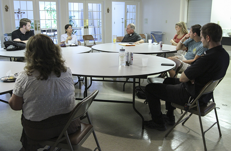 Members of the Catholic Center at the University of Georgia, Athens, conduct a June 4 transitional meeting with incoming priests Father Brian McNavish, foreground right, and Father Fred Wendel, background, right center. Effective July 1, Father McNavish will serve as the assistant director and Father Wendel will be the director. Photo By Michael Alexander