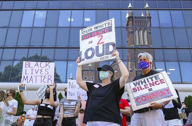 Standing across the street from the Shrine of the Immaculate Conception, Atlanta, (l-r, holding signs) sibling teens Emily and Arely Ramirez from St. Patrick Church, Norcross, and Lisa and Bruce Downs from Prince of Peace Church, Flowery Branch, display signs as they gather with hundreds of other Catholics for a June 11 march for racial justice from the church to Centennial Olympic Park. Photo By Michael Alexander