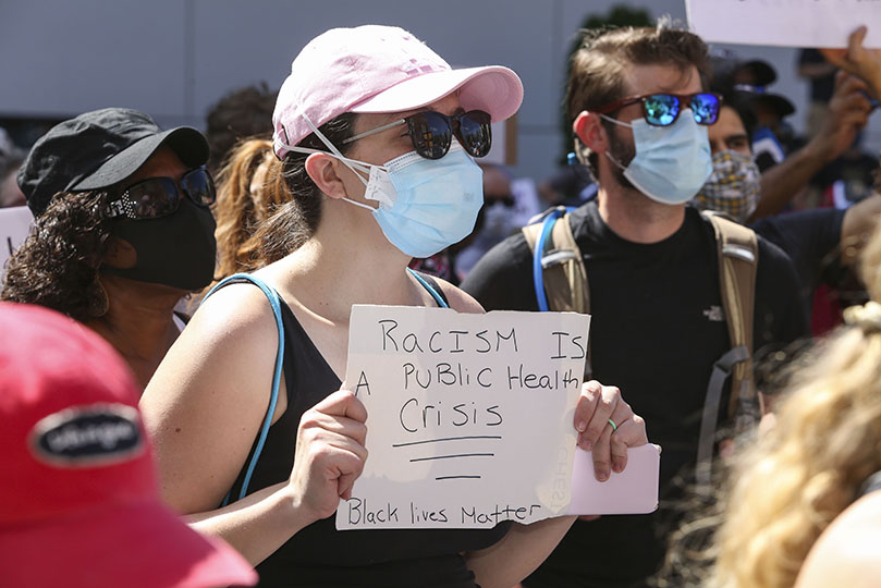 A young woman stands in the street during the Scripture reading, litany and opening prayer that took place prior to the march for racial justice by hundreds of Catholics through downtown Atlanta. Photo By Michael Alexander