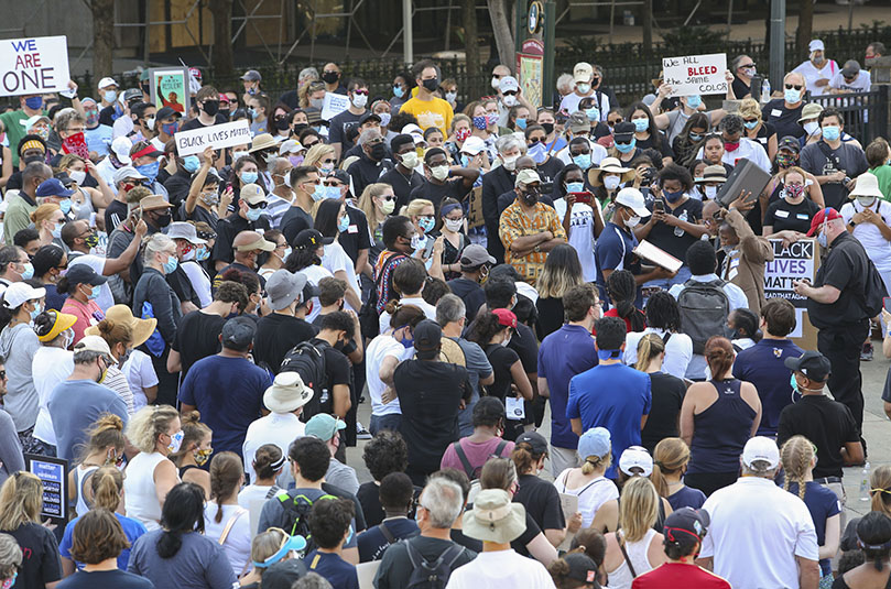 Catholic marchers gather at the entrance to Centennial Olympic Park, the final destination of the march for racial justice. In this photo, Deacon Nicholas Goodly of St. John the Evangelist Church, Hapeville, proclaims the Gospel from the Book of John. Photo By Michael Alexander