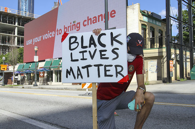 In a final sign of solidarity, Catholics like Josh Bland, a 29-year-old member of the Cathedral of Christ the King, Atlanta, took a knee for 8 minutes and 46 seconds of silence. Bland's wife stood behind him, holding their nine-month old son as the moment unfolded. Photo By Michael Alexander