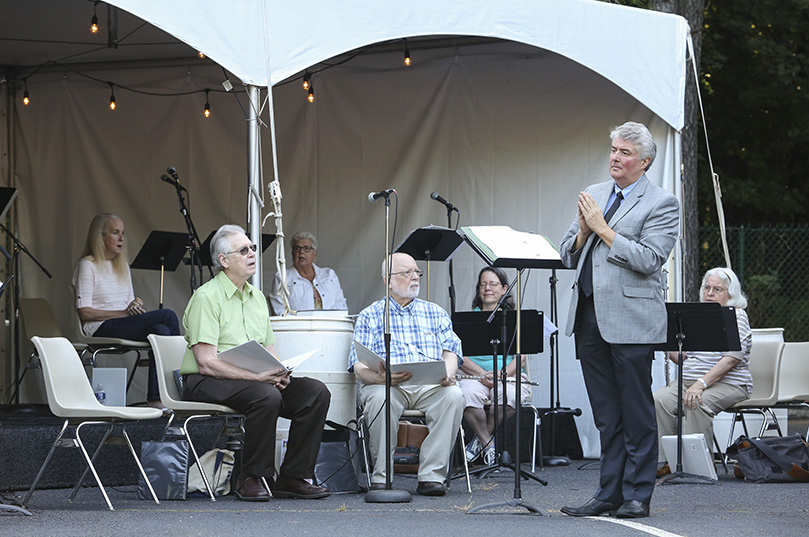 Eric Alexander, standing right, St. Thomas Aquinas Church minister of music, waits for the completion of the first reading before directing the choir during the responsorial psalm at the 9 a.m. outdoor Mass on Sept. 6. The parish started offering one Mass inside the sanctuary at 7 p.m. on Sept. 20. Photo By Michael Alexander