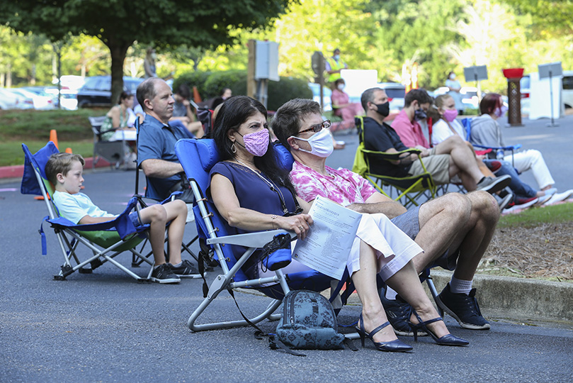 Renee and Bill Cotton are seated in their lawn chairs after the offertory collection and just before standing for the Liturgy of the Eucharist. They were among the more than 400 people in attendance for the Sept. 6, 9 a.m. outdoor Mass in the lower parking lot at St. Thomas Aquinas Church, Alpharetta. Photo By Michael Alexander