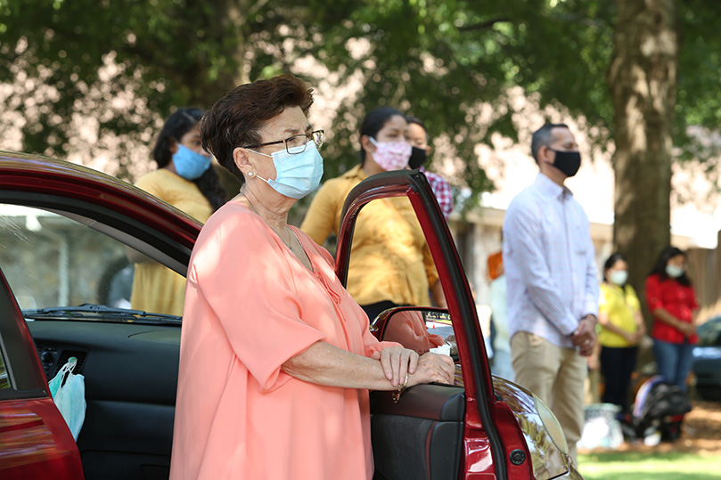 While standing during the Liturgy of the Eucharist, Matilde Cristo leans on her car door. Cristo was among the hundreds of parishioners on hand for the Sept. 6, 11 a.m. outdoor Mass at St. Thomas Aquinas Church, Alpharetta. Photo By Michael Alexander