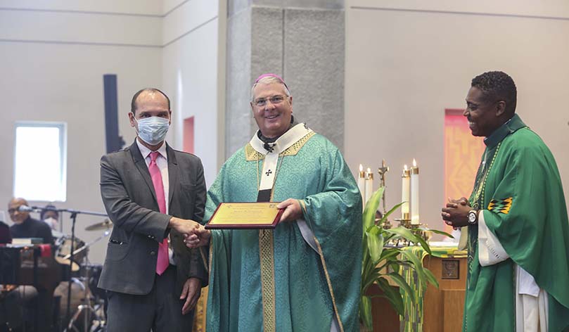 Archbishop Gregory J. Hartmayer, OFM Conv., center, presents an award on behalf of Lyke House to Rudy Schlosser, left, for his years of service in campus ministry. Schlosser is the assistant campus minister for Lyke House and Georgia State University. Smiling off to the side is Father Urey Mark, Lyke House chaplain and director. Years ago, Schlosser was the youth minister at St. Philip Benizi Church, Jonesboro, when the archbishop was the pastor. Photo By Michael Alexander