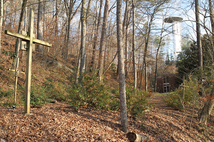 The area below this trail, down along the north ridge to the Chattahoochee River deck and the water’s edge, is where phase five of the Ignatius House work will take place. In the background, up on the hill, is the cell tower and outdoor Montserrat Chapel. Just below that is the retreat house and in the foreground, left, are two Stations of the Cross. Photo By Michael Alexander