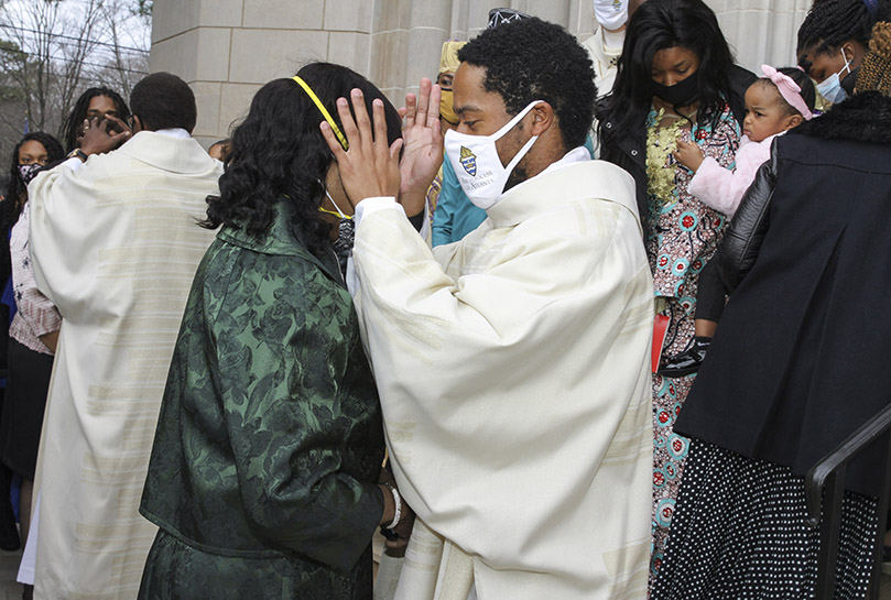 Transitional deacon Avery Daniel, right, extends the first blessing to his mother Phyllis. Daniel grew up in the parish community of Sts. Peter and Paul Church, Decatur. He is currently assigned at St. Peter Chanel Church, Roswell.  Photo By Michael Alexander