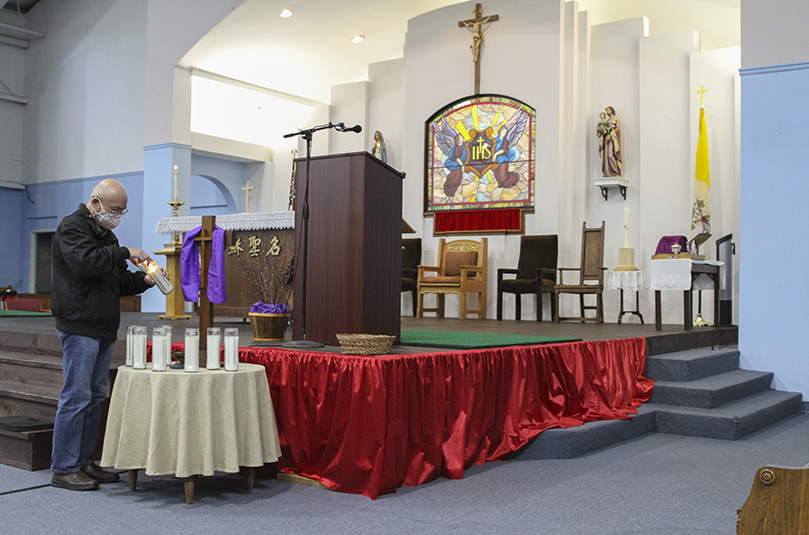 At the beginning of the 10:30 a.m. Mass, March 21, at Holy Name of Jesus Chinese Catholic Mission, Norcross, Andrew Shen, a native of Taiwan, lights one of the eight candles in remembrance of the eight victims killed in the March 16 mass shooting at three Atlanta-area massage parlors. Six of the eight victims were Asian. Photo By Michael Alexander