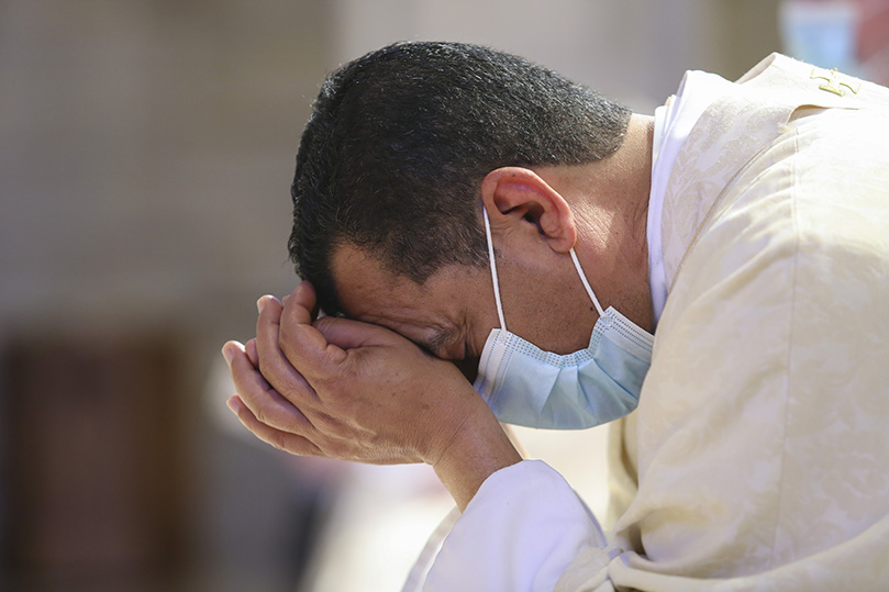 Father José González, parochial vicar at St. John the Evangelist Church, Hapeville, prays as the altar is prepared for the Liturgy of the Eucharist. Father González is one of the 2021 jubilarians celebrating 25 years as a priest. Photo By Michael Alexander