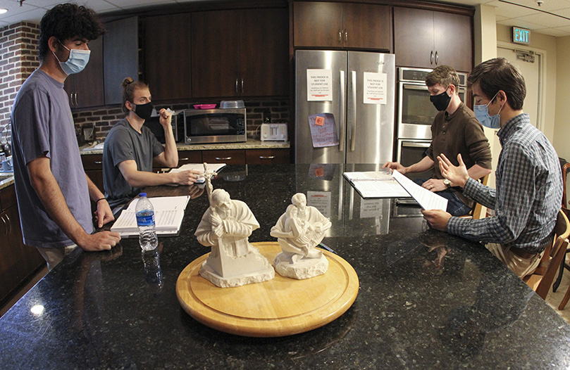 (Clockwise, from left) Terrence Connors, Greg Leopold, Connor Lawson, and Ben Dollar, the male members of the Concordi Laetitia Choir, sequester themselves from the rest of the choir during practice in order to rehearse their parts. Choir rehearsal occurs inside the Catholic Center chapel on the Georgia Tech campus. Conners and Leopold are graduates of Georgia Tech and Lawson is currently a graduate student there. Before the choir was formed, they were among the eight individuals who sang together during Mass at the Catholic Center. Photo By Michael Alexander