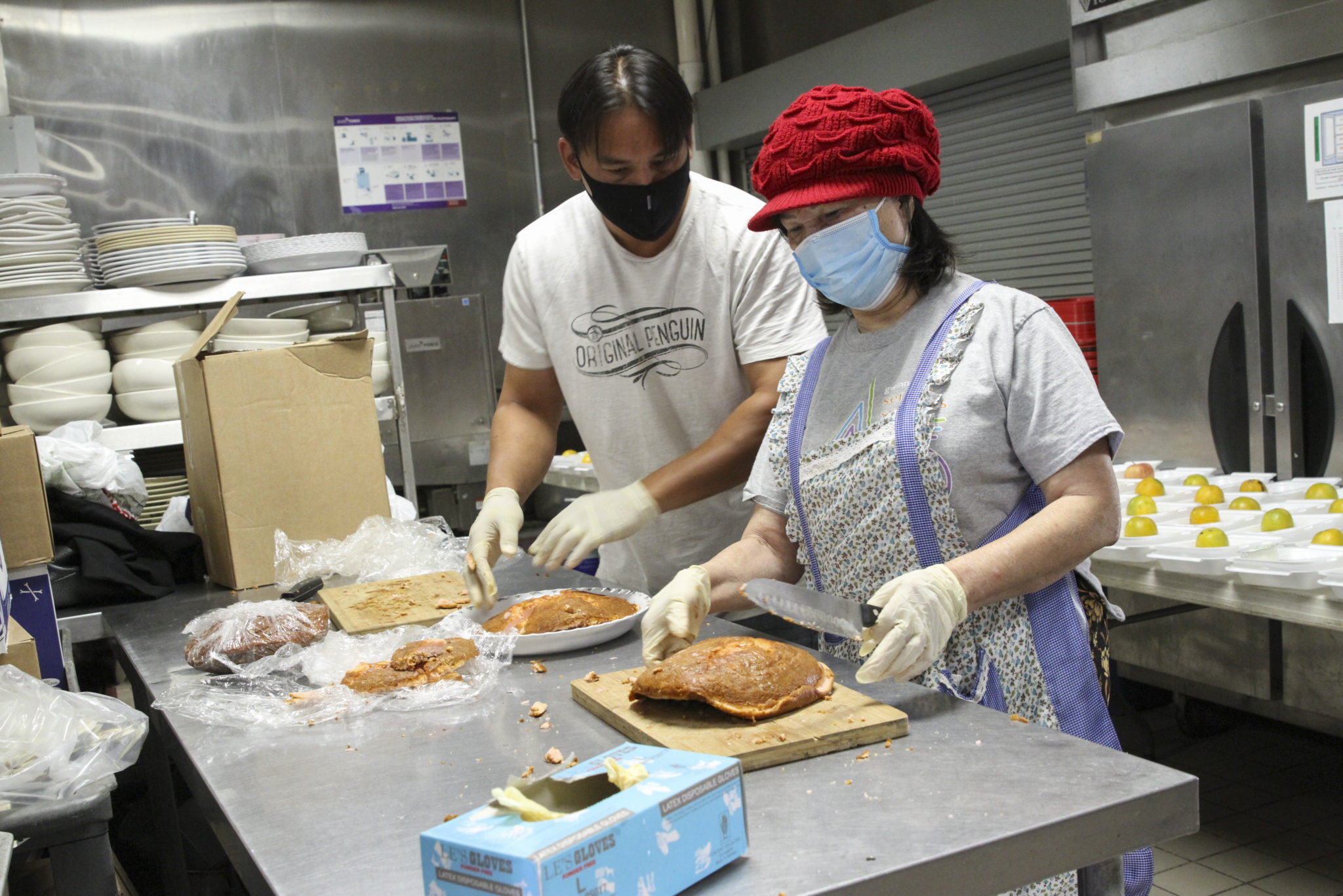 Henry Lam, left, and volunteer Lan Nguyen cut up cake, donated by Caf Intermezzo, into single servings. Lam started the feeding the homeless program in his home, but when it grew to be too big, the pastor at Holy Vietnamese Martyrs Church, Father Francis Tran, allowed him to do all the prep work from the church kitchen. Photo By Michael Alexander