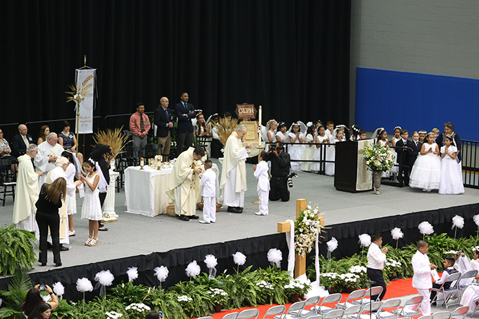 Father Rafael Carballo, left, the current pastor of Our Lady of Perpetual Help Church, Carrollton, and Father Richard Morrow, the founding pastor, distribute holy Communion to two more first communicants. Photo by Michael Alexander