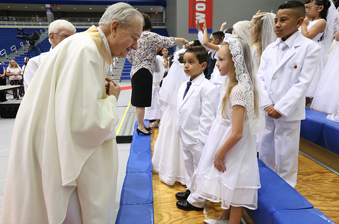 Senior priest Father Richard Morrow introduces himself to two of the 76 youngsters from Our Lady of Perpetual Help Church, Carrollton, before the May 1 Mass at the University of West Georgia Coliseum, where they made their first holy Communion. Father Morrow, the founding pastor of Our Lady of Perpetual Help Church over 50 years ago, was also presented with a rock-carved icon of Our Lady of Perpetual Help during the Mass. Photo by Michael Alexander