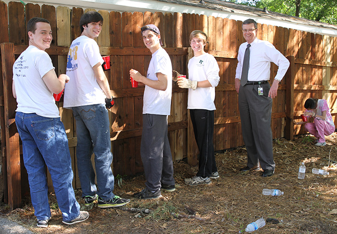 Frank Moore, principal of Roswell’s Blessed Trinity High School, stops by the senior service day project at HomeStretch, a temporary housing community in Roswell where homeless families reside until they can get back on their feet. Since 2007 Blessed Trinity senior classes have cleaned and spruced up the grounds of Homestretch as a community service undertaking. Standing with Moore as they take a break from staining a fence are (l-r) Jon Anderson, Dallas Downing, Ben Drabik and Robby Gipson. Photo By Michael Alexander