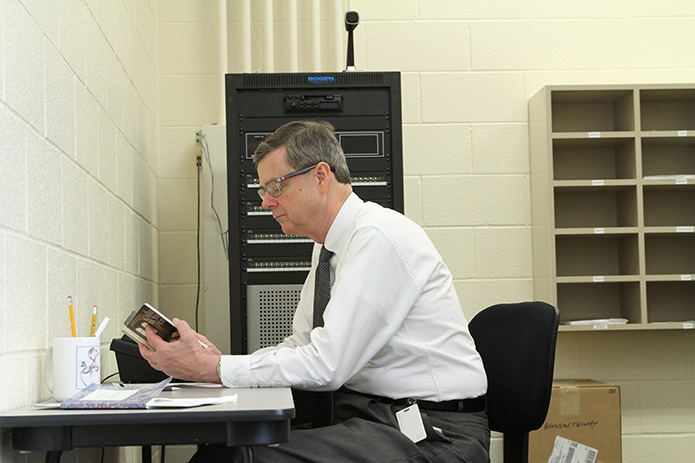 Frank Moore leads off the morning announcements, April 19, with a prayer entitled “The Finger of God.” It was written by 17th century Franciscan nun, Mary of Agreda. Here he looks over the prayer just before making the announcements. Photo By Michael Alexander