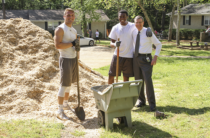 Blessed Trinity High School's Logan Craighead, left, and Emeke Okobah, center, take a break from loading and moving mulch to a playground during their senior service day project to pose with Frank Moore. Photo By Michael Alexander