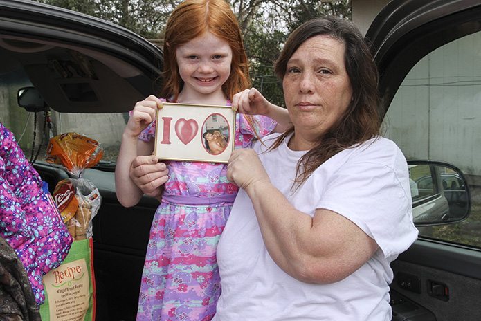 Melissa Sandoval and her 6-year-old granddaughter Hailee hold a photo of Melissa’s husband Domingo, a Mexican detainee, as they prepare to leave El Refugio after an overnight stay. After loading the truck with their belongings, they were planning to stop by the Stewart Detention Center to visit Domingo before driving back to Rome, Ga. Photo By Michael Alexander