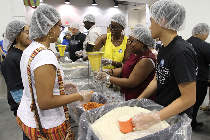 (Clockwise, starting third from right) Denise Bernard of Most Blessed Sacrament Church, Atlanta, pours in a cup of dehydrated soy, one of four items added to the meal bags, as she teams up with fellow parishioner Sherley Vieux, Thinh Nguyen of the Holy Vietnamese Martyrs Church, Norcross, Elizabeth Nunes and Jennifer Ayala of Holy Spirit Church, Atlanta, during Starve Wars at the Georgia International Convention Center, College Park. Photo By Michael Alexander