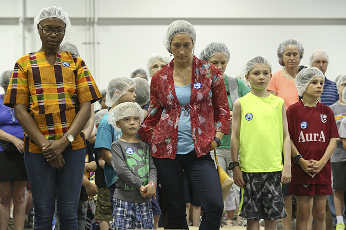 (L-r) Adesuwa Inneh of St. Philip Benizi Church, Jonesboro, Vander Stelten, 5, his mother Erica of St. Thomas More Church, Decatur, Liam Viets, 11, and his brother Colin, 9, of Transfiguration Church, Marietta, stand with 295 other volunteers as Father Victor Galier, pastor of St. Anthony of Padua Church, Atlanta, leads the group in a prayer before the second session of Starve Wars gets underway. Photo By Michael Alexander