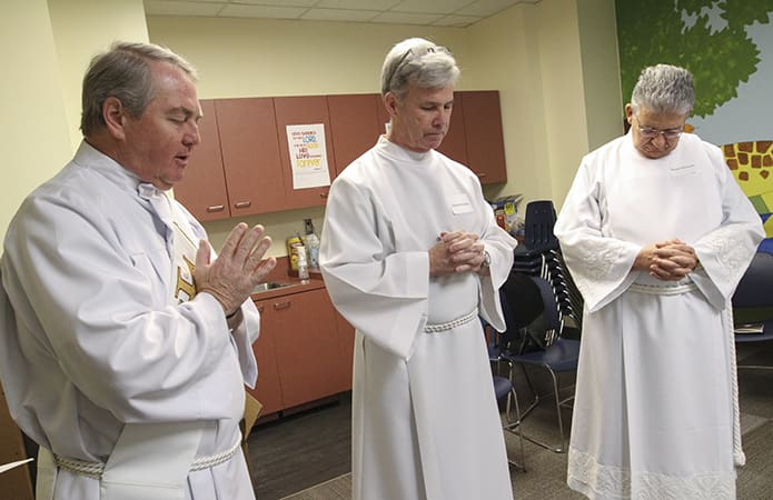 Prior to the ordination, Deacon Steve Swope, far left, from Saint George Church, Newnan, stops by to pray with the 10 permanent diaconate candidates. The year’s candidates were the last to come through when he was the director of formation in the Office of the Permanent Diaconate. Standing with him are Edward Buckley, center and Manuel Echevarria, of St. George and St. John Neumann Church, Lilburn, respectively. Photo By Michael Alexander