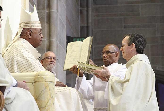 Archbishop Gregory presents the Book of Gospels to Deacon James Paul Wolf. Deacon Wolf is assigned to serve at St. Brigid Church, Johns Creek. Photo By Michael Alexander