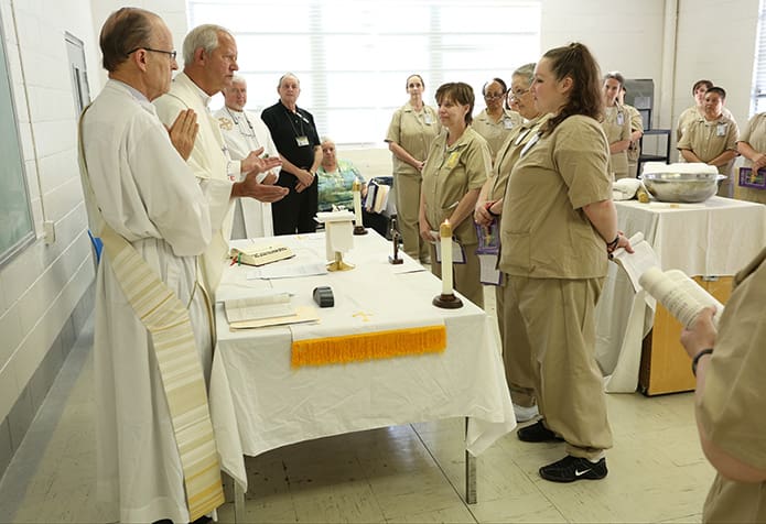 Father Thad Rudd, second from left, addresses the baptism candidates (foreground to background) Felicia Nicole Greenway, Carla Rae Hopwood and Beverly Dawn Barber as they stand before the altar, May 6. Photo By Michael Alexander