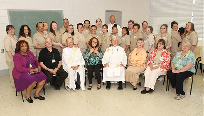 Members of St. Joseph Cafasso Prison Ministries out of St. Thomas Aquinas Church in Alpharetta including (l-r, sitting) Dolly Fairclough, Paul Caruso, Deacon Bernard Casey and Catherine Boys of St. Thomas Aquinas Church, Msgr. William Hoffman, retired, Marge Pizzolato of St. Peter Chanel Church, Roswell, and Ginny Smith of St. Michael the Archangel Church, Woodstock, and Susan Bishop, Lee Arrendale State Prison clinical chaplain, join Father Thad Rudd, retired, back row, third from the right, and all the inmates who attended the May 6 liturgy for a group photograph. Photo By Michael Alexander