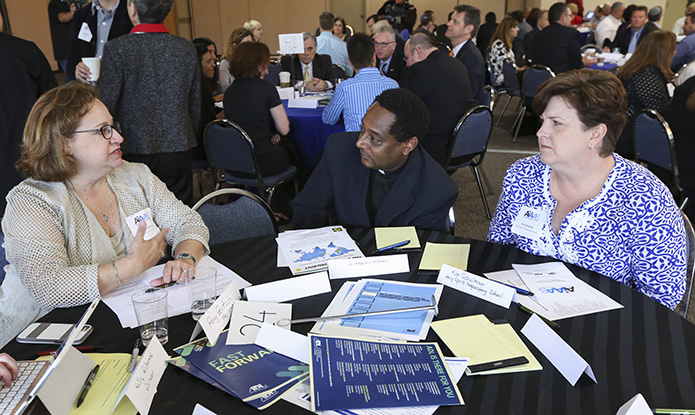 (R-l) Kim Shulman, director of communication at Holy Spirit Church, Atlanta, and Father Tamiru Atraga, parochial vicar at Holy Spirit Church, listen as table facilitator Amy Feintuch of Temple Emanu-El shares with the group. Photo By Michael Alexander