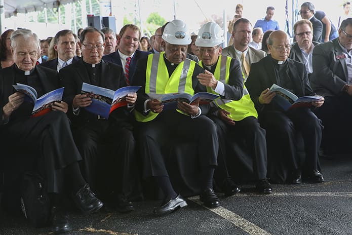 Holy Vietnamese Martyrs Church pastor Father Francis Tuan Tran, front row, third from right, points out the architectural drawings of the proposed church to Archbishop Gregory in a commemorative booklet that was passed out during a program after the Mass. Photo By Michael Alexander