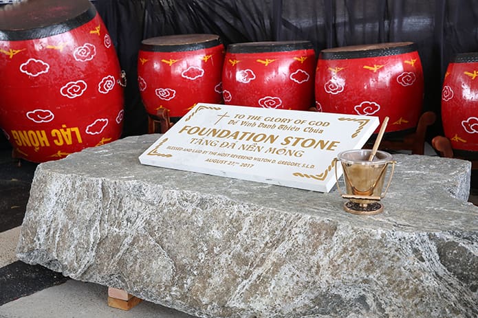 Holy water sits atop the granite foundation stone, which was blessed by Archbishop Wilton D. Gregory after his homily. Once the foundation stone is sand blasted with the wording that appears in gold letters on the white display, it will become a part of the new church. Photo By Michael Alexander