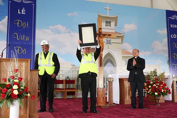 Father Francis Tuan Tran proudly shows off the proclamation from the Archdiocese of Atlanta to the vast congregation. Photo By Michael Alexander