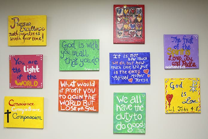 Handmade plaques created by Cristo Rey Atlanta students, bearing Scripture or inspirational messages, are prominently displayed on the school’s administrative floor, opposite the elevators. Photo By Michael Alexander