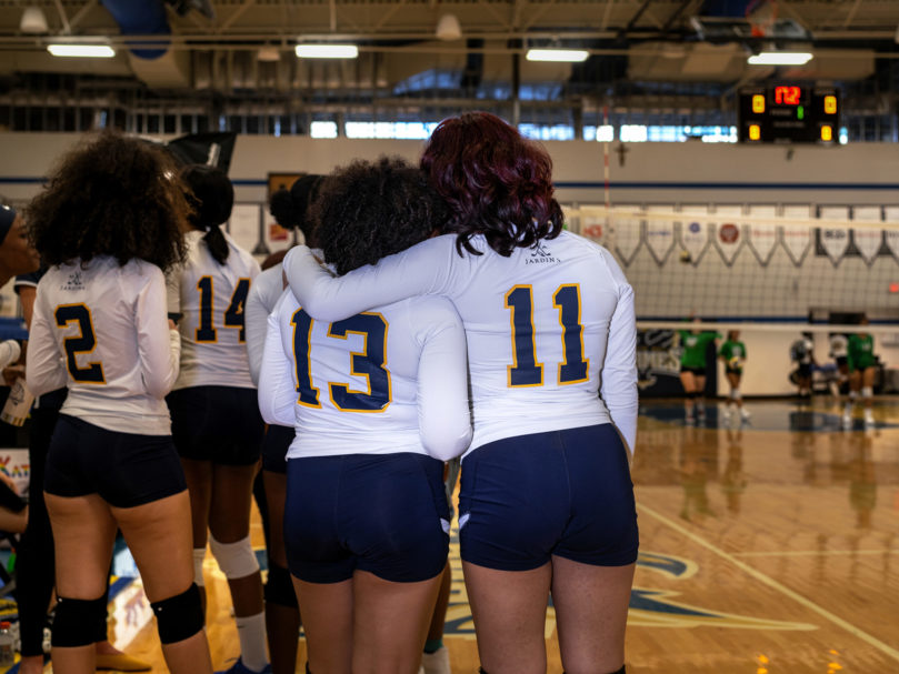 Kiera Jones (#13) and Cynthia Bello (#11) of The Cristo Rey Flames huddle together after an opening team prayer. Photo by Johnathon Kelso