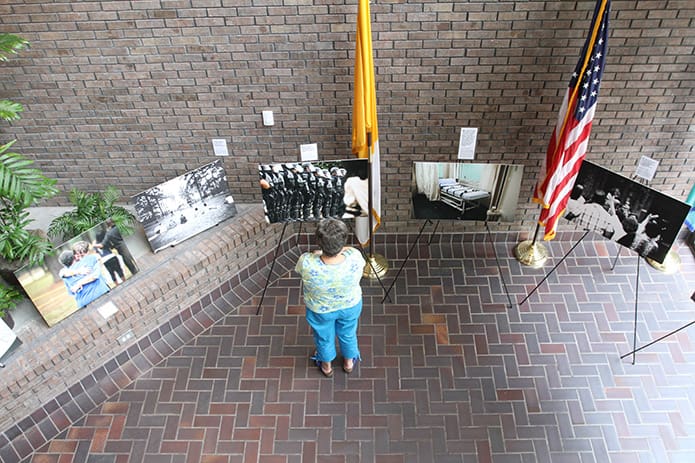 During a break Christiane Belisle of St. Joseph Church, Macon, where she serves as the respect life chair, stands before one of the 21 photos documenting the timeline of an execution. The exhibit, the work of freelance photojournalist Scott Langley, is called a âJourney Into the U.S. Death Penalty.â Photo By Michael Alexander