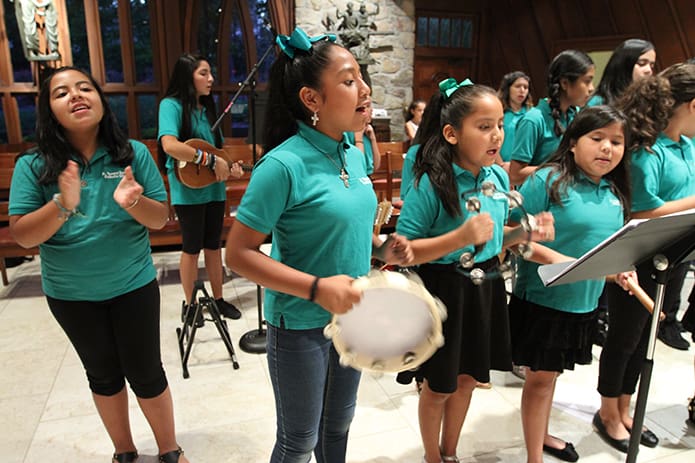 (Foreground, left to right) Kimberly Ramirez, Mariana Perez, Danna Contreras and Karen Mora sing the closing hymn during the evening Spanish Mass. Photo By Michael Alexander