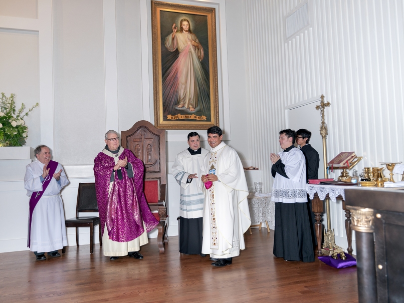 Archbishop Gregory J. Hartmayer, OFM Conv., second from left, applauds Father Peeter Pedroza, center, during the dedication service at Divine Mercy Mission. Father Pedroza is the mission's administrator. Photo by Johnathon Kelso