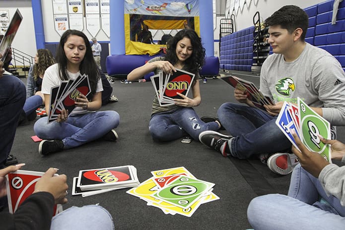 (L-r) Stephanie Villasenor, Julia Sanchez and Kevin Burgos-Trujillo, Cristo Rey Atlanta seniors, play a game of Uno with supersized cards, one of several activities and games available to them during the May 15 senior picnic. Villasenor, Sanchez and Burgos-Trujillo will be attending Georgia State University, Atlanta, St.  Mary’s College, Notre Dame, Ind., and Life University, Marietta, respectively. Photo By Michael Alexander