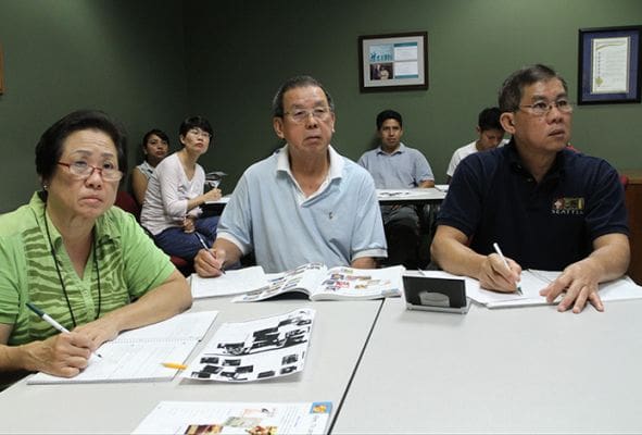 Njuk Jong, her husband Kusok Pak and Freddy Hendrawan study the sentences on the board each person took a turn constructing in English. The three students are from Indonesia. Photo By Michael Alexander