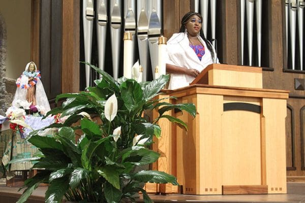 Genevieve Cardos, a sophomore student at Spelman College, Atlanta, sings the responsorial psalm “Jemong Xek Bi Mariama (Mary the Gem)” as the statue of Mary that was carried in during the procession looms in the background. Photo By Michael Alexander