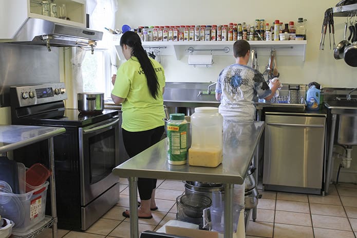 One resident stands over the stove watching the pasta boil and the other resident stands by the sink as they prepare lunch for the other residents. GraceWay residents take responsibility for and perform all daily household tasks, including healthy meal preparation and cleanup. Photo By Michael Alexander