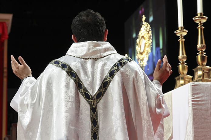 Father Carlos Vargas, pastor of Good Samaritan Catholic Church, Ellijay, kneels before the real presence of Jesus displayed on the altar. Father Vargas joined Father Tim Hepburn during adoration and the healing service on the opening evening of the 23rd annual Eucharistic Congress. Photo By Michael Alexander