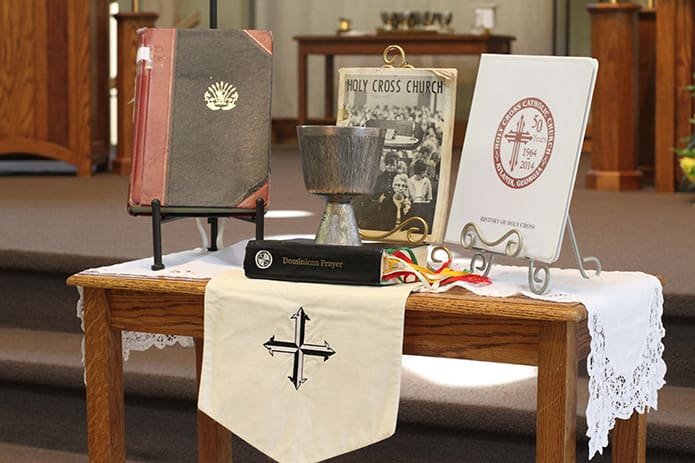 Articles such as the first parish registry, the first church directory, the chalice used during the first Mass, a binder containing the history of the church and a Dominican prayer book were carried by parishioners to the front of the church during the opening procession of the 50th anniversary foundersâ Mass, July 26. Photo By Michael Alexander