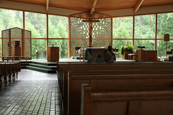 “Our large Church window is a vista into Gods creation outside,” said Father Darragh Griffith, the pastor of Holy Family Church, Marietta. One morning two women could be found sitting before the altar in prayer. Photo By Michael Alexander